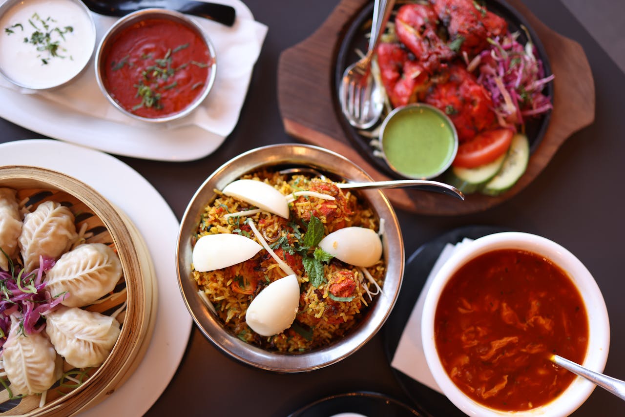 A colorful spread of Indian cuisine featuring biryani, momos, and sauces, perfect for a culinary adventure.